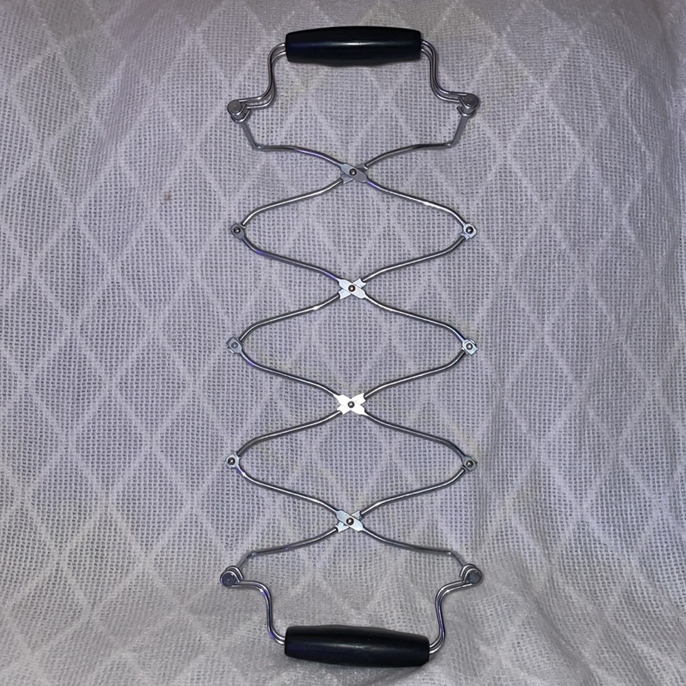 Expandable trivet with black rubber handles. - Picture 2 of 3